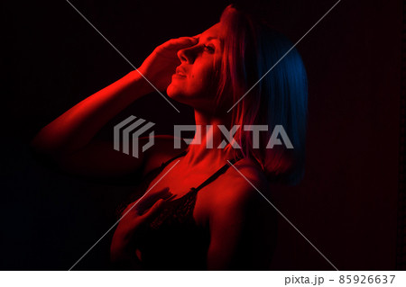 portrait of a blonde girl close-up in a room with red and blue light. portrait of a blonde girl close-up in a room with red and blue light. 85926637