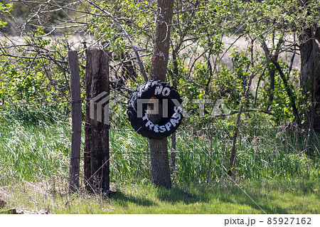 No Trespassing tire sign on barb wire fence  85927162
