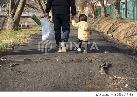買い物袋を持ち子供と歩く男性の後ろ姿 買い物袋を持ち子供と歩く男性の後ろ姿 85927448