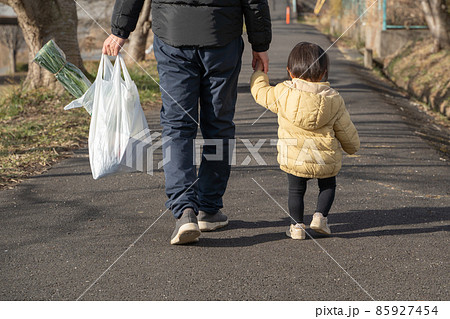 買い物袋を持ち子供と歩く男性の後ろ姿 買い物袋を持ち子供と歩く男性の後ろ姿 85927454