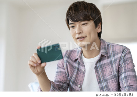 スマートフォンの画面を見る30代の男性 スマートフォンの画面を見る30代の男性 85928593