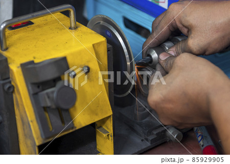 The worker regrinding the end mill tool with end mill sharpening machine. The worker regrinding the end mill tool with end mill sharpening machine. 85929905