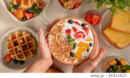 A female hands holding a smoothie yogurt bowl over table. 85931625