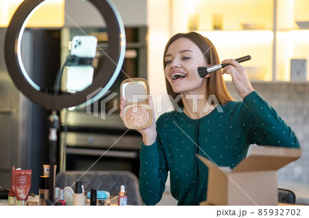 Woman holding face brush and doing make up Woman holding face brush and doing make up 85932702