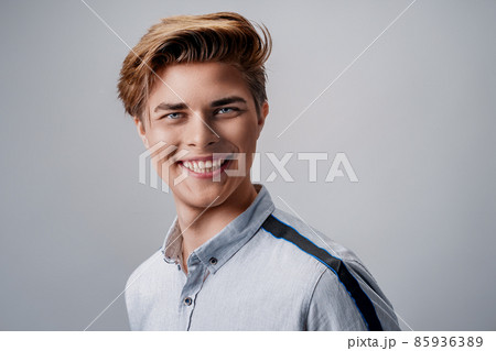 portrait of handsome young guy wearing shirt while looking at camera and smiling Stylish hairstyle.  85936389