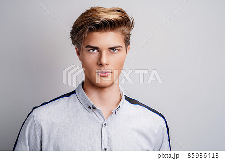 portrait of handsome young man wearing shirt while looking at camera. Stylish hairstyle. portrait of handsome young man wearing shirt while looking at camera. Stylish hairstyle. 85936413