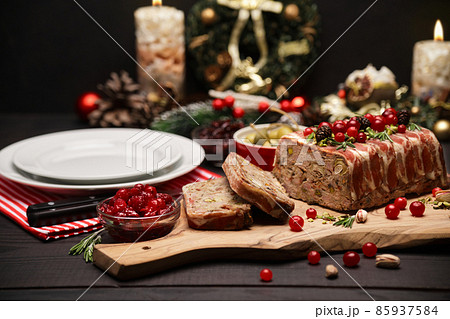 Traditional French terrine covered with bacon on dark wooden background with Christmas decorations 85937584