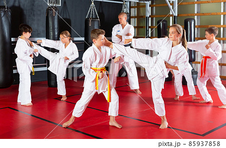 Kids working in pair, mastering kicks in karate class 85937858