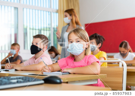 Kids in masks studying in classroom 85937983