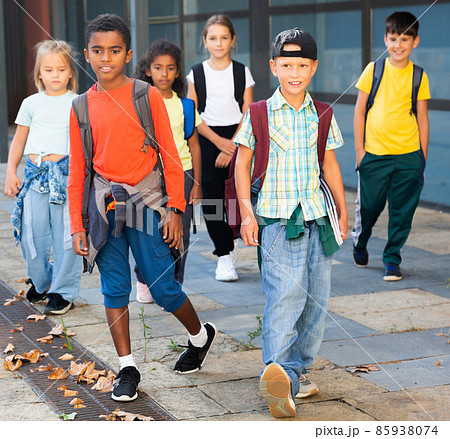 Smiling tweenagers walking outside school building on autumn day Smiling tweenagers walking outside school building on autumn day 85938074