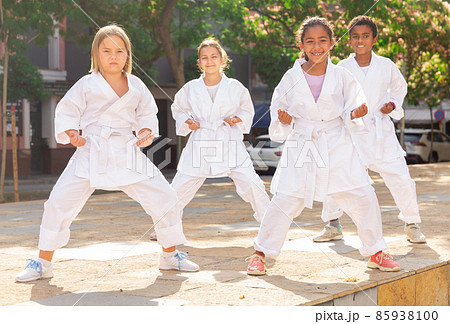 Multiracial group of tweens practicing karate on summer city street 85938100