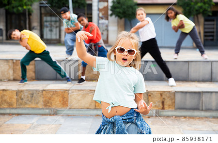 Blonde preteen b-girl dancing with friends on city street Blonde preteen b-girl dancing with friends on city street 85938171