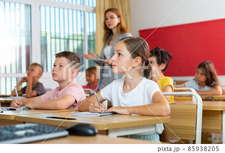 Diligent tween schoolgirl making notes of teacher lecture 85938205
