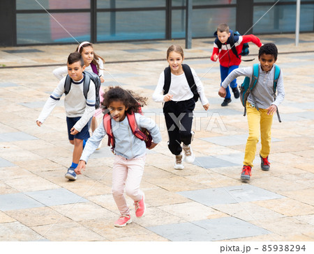 Group of cheerful tweenagers running in school yard after lessons Group of cheerful tweenagers running in school yard after lessons 85938294
