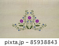 Embroidery of a bouquet with purple clementine flowers and delicate violets on a beige fabric background. 85938843
