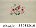 Embroidery of a delicate bouquet with sprigs of red-pink roses and delicate violets on a beige fabric background 85938919