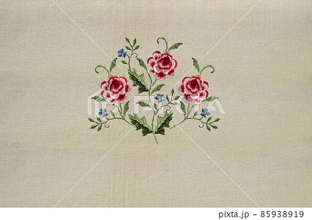 Embroidery of a delicate bouquet with sprigs of red-pink roses and delicate violets on a beige fabric background 85938919