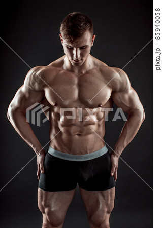 Muscular bodybuilder guy doing posing over black background Muscular bodybuilder guy doing posing over black background 85940058