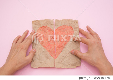 love concept - female hands stick together torn red heart on paper on pink background 85940170