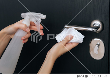 Cleaning black door handles with an antiseptic wet wipe and sanitizer spray. Disinfection in hospital and public spaces against corona virus. Woman hand using towel for cleaning home room door link. 85941296