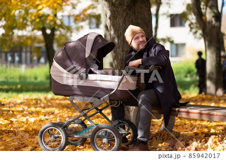 Happy young father with pram during the walk in nature Happy young father with pram during the walk in nature 85942017
