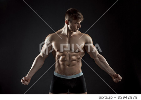 Muscular bodybuilder guy doing posing over black background Muscular bodybuilder guy doing posing over black background 85942878