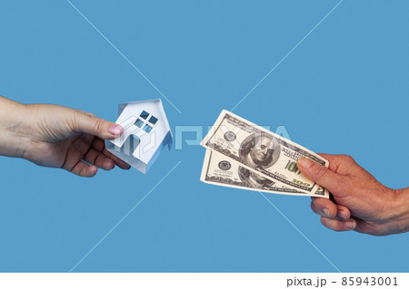 Hands with a toy house and money. Dollars. 85943001