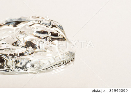 Transparent hyaluronic acid gel drop on a beige background. 85946099