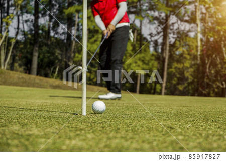 Golfer putting golf ball on golf green The glare of the lens at dusk at sunset. 85947827