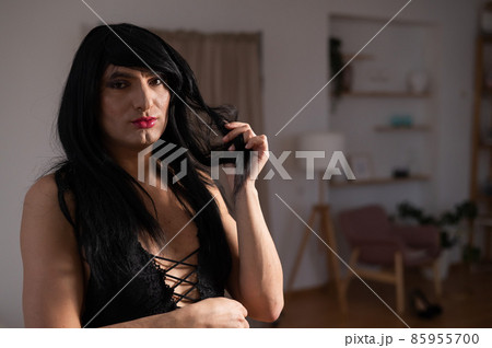 Homosexual preening in front of the mirror. A transgender man combing a wig. 85955700