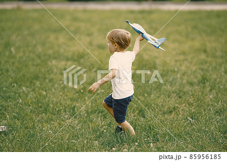 Little boy playing with airplane toy on a grass Little boy playing with airplane toy on a grass 85956185