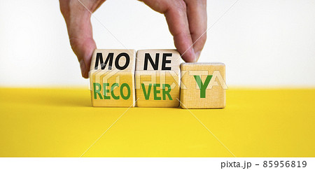 Money recovery symbol. Businessman turns wooden cubes and changes the word money to recovery. Beautiful yellow table, white background, copy space. Business and money recovery concept. 85956819
