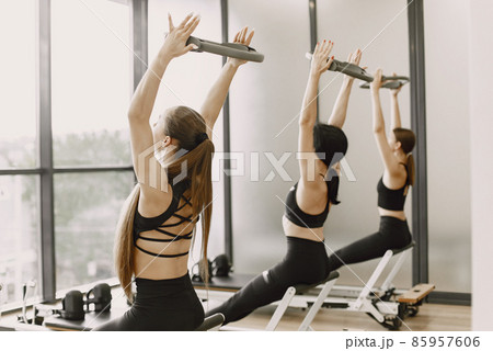 Three girls in a bright gym stretching with equipment Three girls in a bright gym stretching with equipment 85957606