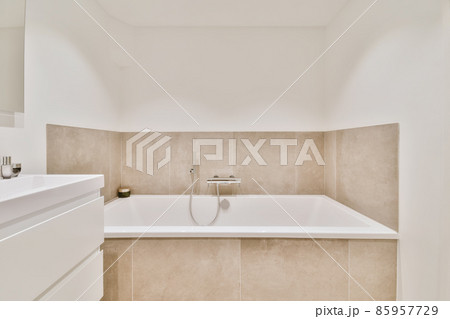 Beautiful bathroom with a big bathtub and white walls Beautiful bathroom with a big bathtub and white walls 85957729