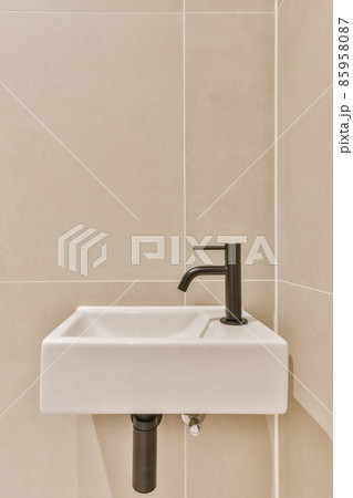Stylish bathroom in a minimalist style in beige and black tones with a small sink 85958087
