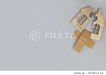 Closeup of broken house figure with crossed band aid on grey background top view, copy space, divorce, relationship problems, moving house, mortgage, 85961114