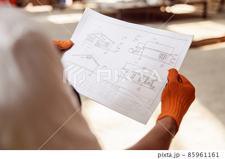 Male builder hands in gloves holding architectural plan Male builder hands in gloves holding architectural plan 85961161