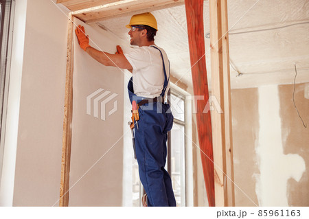 Male worker hanging wallpaper on the wall Male worker hanging wallpaper on the wall 85961163