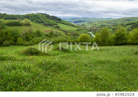 wonderful countryside rural landscape. beautiful view of idyllic mountain scenery in the carpathians. fresh green forests and meadows. overcast rainy morning. village in the distant valley wonderful countryside rural landscape. beautiful view of idyllic mountain scenery in the carpathians. fresh green forests and meadows. overcast rainy morning. village in the distant valley 85962028