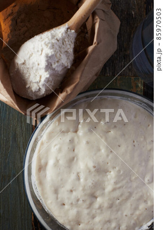 Wheat flour starter culture is ready to be added to the dough. Spoon with flour and water on the table. Top view. 85970503