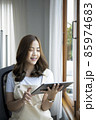Smiling young asian woman using digital tablet at home office. 85974683