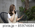 Asian woman using digital tablet and talking on mobile phone at outdoor cafe. 85974684
