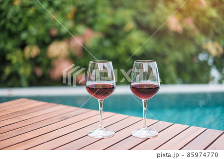Two Red wines glasses near swimming pool. Summer travel, vacation, holiday and happy weekend concept Two Red wines glasses near swimming pool. Summer travel, vacation, holiday and happy weekend concept 85974770