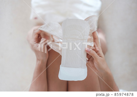 woman hands holding sanitary pad or menstruation napkin during wearing it. Menses, feminine, menstrual period, monthly period and personal hygiene concepts woman hands holding sanitary pad or menstruation napkin during wearing it. Menses, feminine, menstrual period, monthly period and personal hygiene concepts 85974878