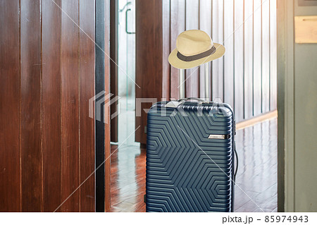 Blue Luggage with hat in modern hotel room after door opening. Time to travel, service, journey, trip, summer holiday and vacation concepts 85974943