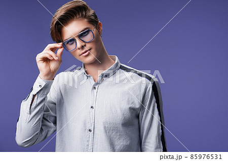 Male hairstyle concept. Hipster man with stylish haircut in sunglasses stands over lilac background. 85976531