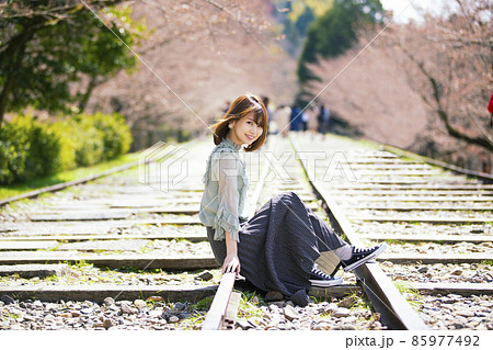 京都府京都市東山区の蹴上インクラインで桜を背景にして線路に腰をかける若い女性 85977492