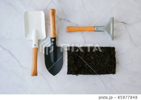 Garden tools. Gardening tools on concrete background flat lay. Plant flowers for garden. Tools spade, fork, hand cultivator, hoe and pot with soil 85977848