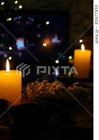 Movie on laptop at night in bedroom lit with candles. Pop corn. Autumn atmosphere at home 85977850