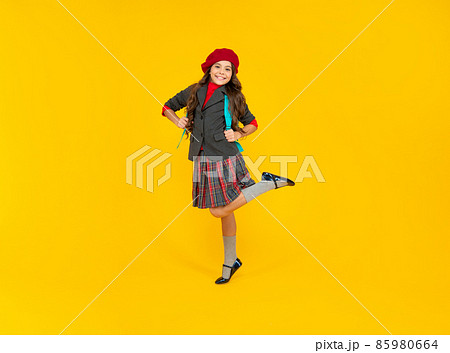 happy kid in school uniform with beret and backpack jump on yellow background, school fashion happy kid in school uniform with beret and backpack jump on yellow background, school fashion 85980664